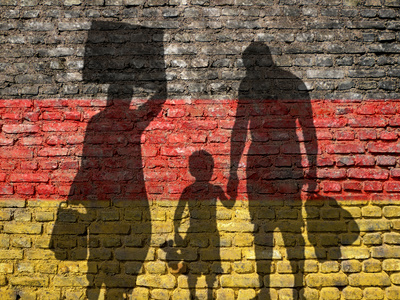 Flüchtlinge in Deutschland Schatten einer Flüchtlingsfamilie vor der Deutschlandflagge